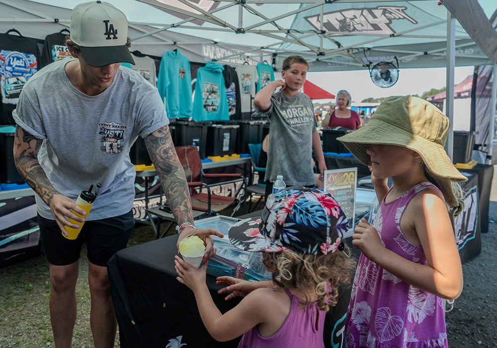 Chevy Reese hands out snow cones to young fans at Smoke, Fire and Thunder
